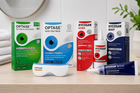 A group of Optase and Hycosan eye care products arranged on a light wood surface, including Optase tea tree oil eye wipes, most heat mask, extra drops, night drops, and a tube, with their retail boxes behind them.