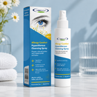 A bottle and box of theeye doctor Hypochlorous Cleansing Spray for Allergy Comfort, displayed on a light marble surface with a blurred background of white daisies and a glass of water.