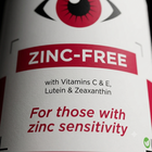 Close-up of a supplement label with a white background, red and black text, and a stylized red eye graphic at the top. The label reads 'ZINC-FREE' and 'For those with zinc sensitivity.