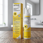 OPTASE Manuka Oil Eyelid Cleansing Gel shown with its yellow and white packaging box and the clear pump bottle, set on a wooden tabletop with a softly blurred bathroom background.