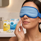 A woman wearing a blue sleep mask and wiping her face with a cotton pad, with Optase Moist Heat Mask boxes visible in the background.