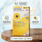 A box of OPTASE Manuka Oil Eyelid Wipes stands on a round wooden surface against a light blue water-themed background. The packaging is yellow and white with a large eye illustration and text highlighting biodegradable tencel wipes, preservative and sulphate free formula, and infusion with manuka oil.