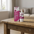 A bottle and box of Hycosan Intens nasal spray placed on a rustic wooden table in a softly lit living room setting.