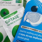 Optase tea tree oil eyelid wipes packaging, showing a blue and white pouch with a clear hydrobead eye patch illustration and a white packet with green accents.