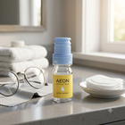 AEON Protect Plus eye drops in a clear bottle with a yellow label and a light blue cap, set on a bathroom counter with folded towels, glasses, and cotton pads nearby.