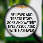A close-up of a magnifying glass over a white label with bold black text reading, 'RELIEVES AND TREATS ITCHY, SORE AND WATERY EYES ASSOCIATED WITH HAYFEVER,' against a blurred green and white background.