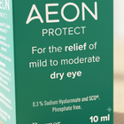 Close-up of a green AEON PROTECT dry eye product box with white text, showing the relief claim and 10 ml size.