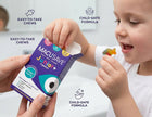 A child is shown opening a box of Macu'save Junior+ gummy chews while an adult hand holds the package. The box is purple and white with a large cartoon eye graphic.