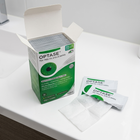 A box of OPTASE Tea Tree Oil Eyelid Wipes sits open on a white bathroom counter, with several individual white and green wipes and a single folded wipe placed in front.
