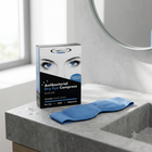 A box of Ophthalmic Antibacterial Dry Eye Compress next to a blue eye mask on a gray stone bathroom counter.