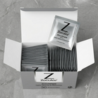 An open white box of Zocular ZocuWipe eyelid cleanser and moisturizer wipes, with several individual packet wipes visible inside and one packet leaning against the open lid, on a gray stone-like surface.