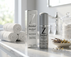 Zocular Foam cleanser bottle and matching box displayed on a bathroom counter with rolled towels, a faucet, and a glass jar in the background.