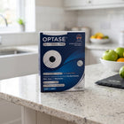 A box of Optase Heat Mask Pro stands on a speckled kitchen countertop with a blurred kitchen background and fruit bowls visible.