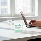 Person using a laptop with a Macusure supplement container on a desk.
